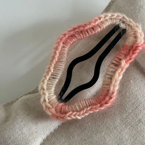 Gros plan sur une pince à cheveux étoile en tricot rose avec une texture laineuse rose et beige