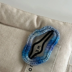Vue détaillée de la texture du crochet dégradé bleu et blanc sur une barrette en métal