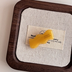 Handmade wavy ginger yellow acetate hair clip in a premium minimalist wooden display