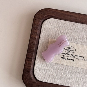 Handmade wavy acetate hair clip in light purple on a rustic display background