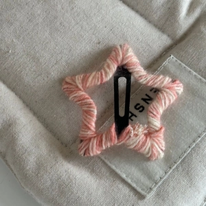 Détail de la pince à cheveux étoile en tricot rose et blanc avec texture en laine douce
