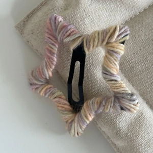 Gros plan sur la barrette étoile en laine crochetée colorée avec base en métal noir
