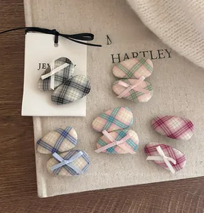 Detailed view of various plaid fabric hair clips with small ribbon bows in diverse colors