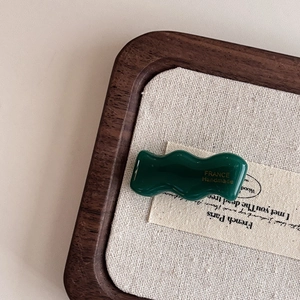 Close-up of wavy dark green acetate hair clip with gold France Handmade logo