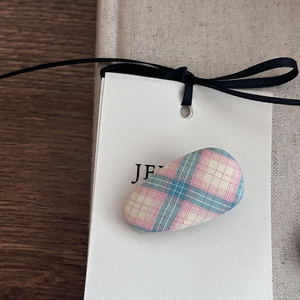Pink and blue plaid oval hair clip with black ribbon bow on white display card
