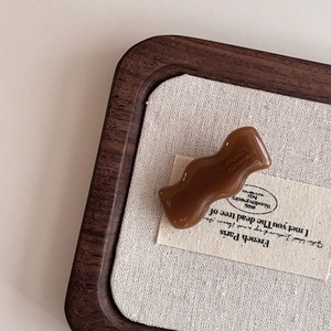 Macro detail of wave acetate hair clip with FRANCE Handmade engraving in caramel