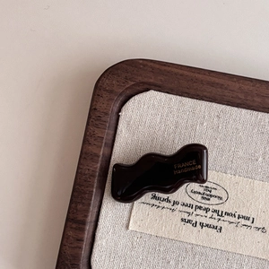Detail showing wavy dark brown acetate hair clip with gold France Handmade lettering