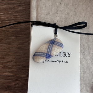 Detail of blue and beige plaid bow hair clip on jewelry card against rustic wood background
