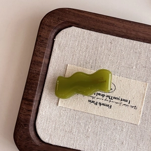 Detail of green acetate wavy hair clip showing smooth texture and handmade craftsmanship
