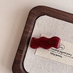 Close-up of deep red wave acetate hair clip with France Handmade gold engraving