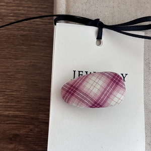 Close-up of pink and white checkered fabric oval hair clip on a jewelry card