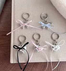 Close-up of silver metal heart and bow charms with colorful ribbons on a book cover