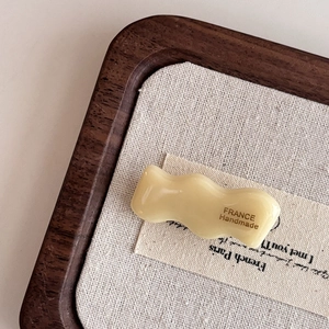 Close-up of cream yellow wavy acetate hair clip with FRANCE Handmade gold lettering
