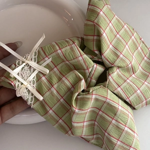 Close-up of blue plaid scrunchie featuring white lace edges and delicate ribbon bows