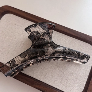 Detail of elegant black lace pattern inside a translucent large hair claw clip