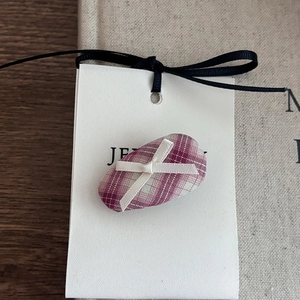 Detailed close-up of a pink plaid bow hair clip on a white display card with silk ribbon