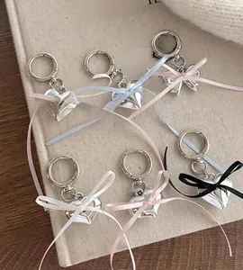 Detail view of silver heart charms with colorful ribbon bows on a textured background