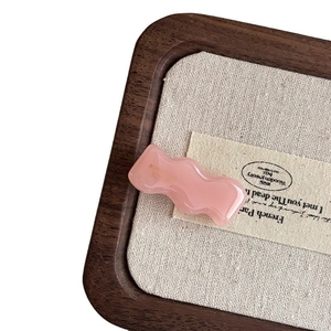 Pink wavy acetate hair clip in a vintage wooden tray with natural linen lining