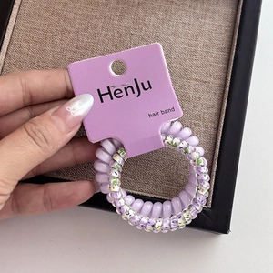 Gros plan d'un élastique spirale violet à fleurs avec son étiquette en papier