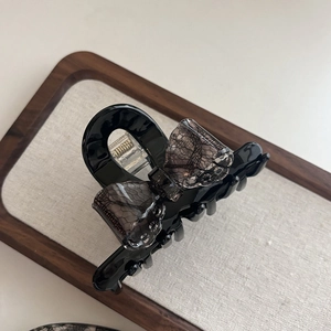 Close-up of black lace bow hair claw clip showing fine mesh details and resin teeth