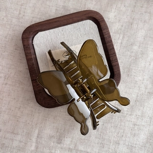 Detailed top view of an amber olive butterfly hair claw clip with golden metal spring