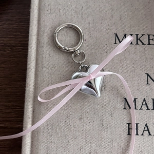 Close-up of polished silver heart pendant with pink silk ribbon on textured fabric