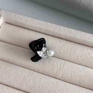 Détail de la petite pince à cheveux noire avec perles et cristaux sur tissu en lin beige