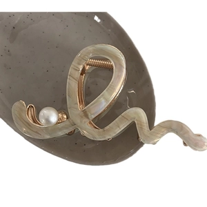 Elegant wavy marbled acetate hair claw clip with pearl detail and gold metal spring