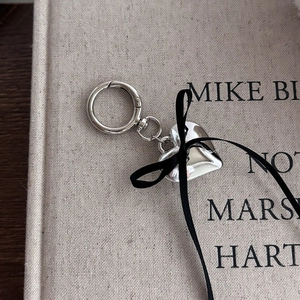 Detail of silver heart keychain with black ribbon bow on a vintage book surface