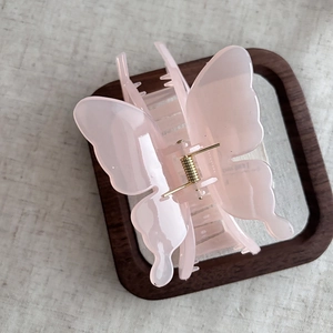 Detailed macro view of the pink butterfly hair claw with a gold metal spring mechanism