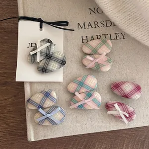 Chic plaid fabric hair clips with small ribbon bows displayed on a textured beige canvas