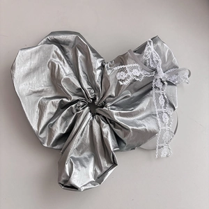 Silver metallic scrunchie featuring an elegant white lace bow decoration and folds