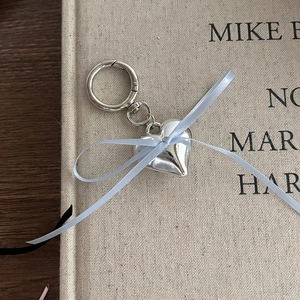 Detailed close-up of a silver heart-shaped keychain with a sweet light blue ribbon bow