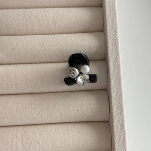 Gros plan d'une mini pince à cheveux noire avec perles et cristal dans un écrin beige