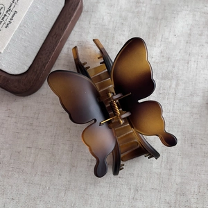 Macro detail of amber butterfly hair claw clip with vintage resin finish and metal spring