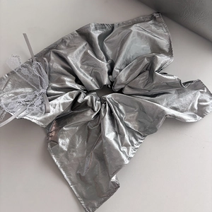 Close-up of a silver metallic scrunchie with white lace trim and ruffled texture detail