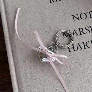 Detail of silver heart pendant with pink ribbon bow and spring ring clasp on fabric