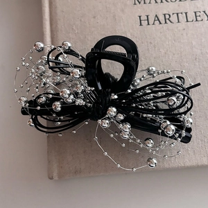Pince à cheveux minimaliste avec chaîne à billes argentées et monture noire sur livre