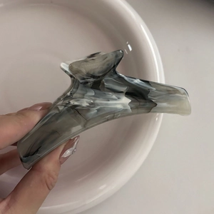 Detailed macro view of the marble pattern grey ink claw clip held by a hand
