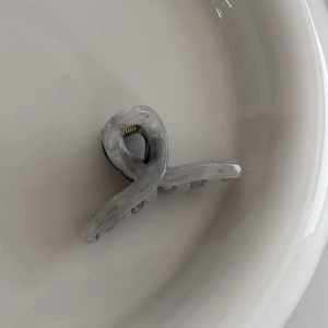 Close-up of marble pattern acetate hair claw clip with golden metal spring on a tray