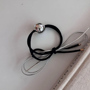 Gros plan sur élastique cheveux noir avec boule argentée et détail de nœud en métal