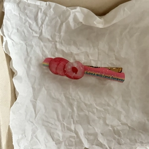 Roze donut haarspeld met de tekst Love will last forever op een metalen ondergrond