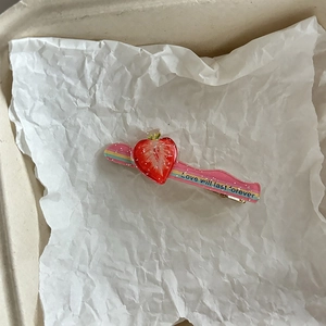 Detailopname van roze gestreepte haarclip met een sprankelende aardbei van acryl