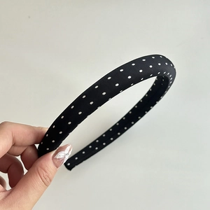 Detail of a vintage black fabric headband with classic white polka dots and thick design