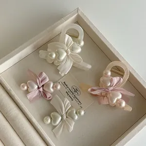 Nahaufnahme von Perlen-Bogen-Haarspangen in Rosa und Creme auf einem Tablett
