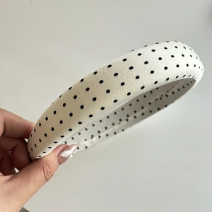 Detailed close-up of a white padded headband with black polka dots in fabric