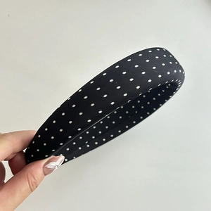 Close-up of a vintage black fabric headband with white polka dots held in hand