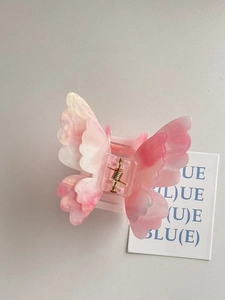 Detailed macro view of butterfly hair claw clip with pink gradient marble acetate texture