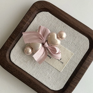 Detail einer rosa Seidenschleife Haarspange mit glänzenden Herzperlen auf Holztablett