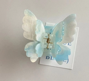 Detailed view of butterfly claw clip with light blue marble texture and gold spring